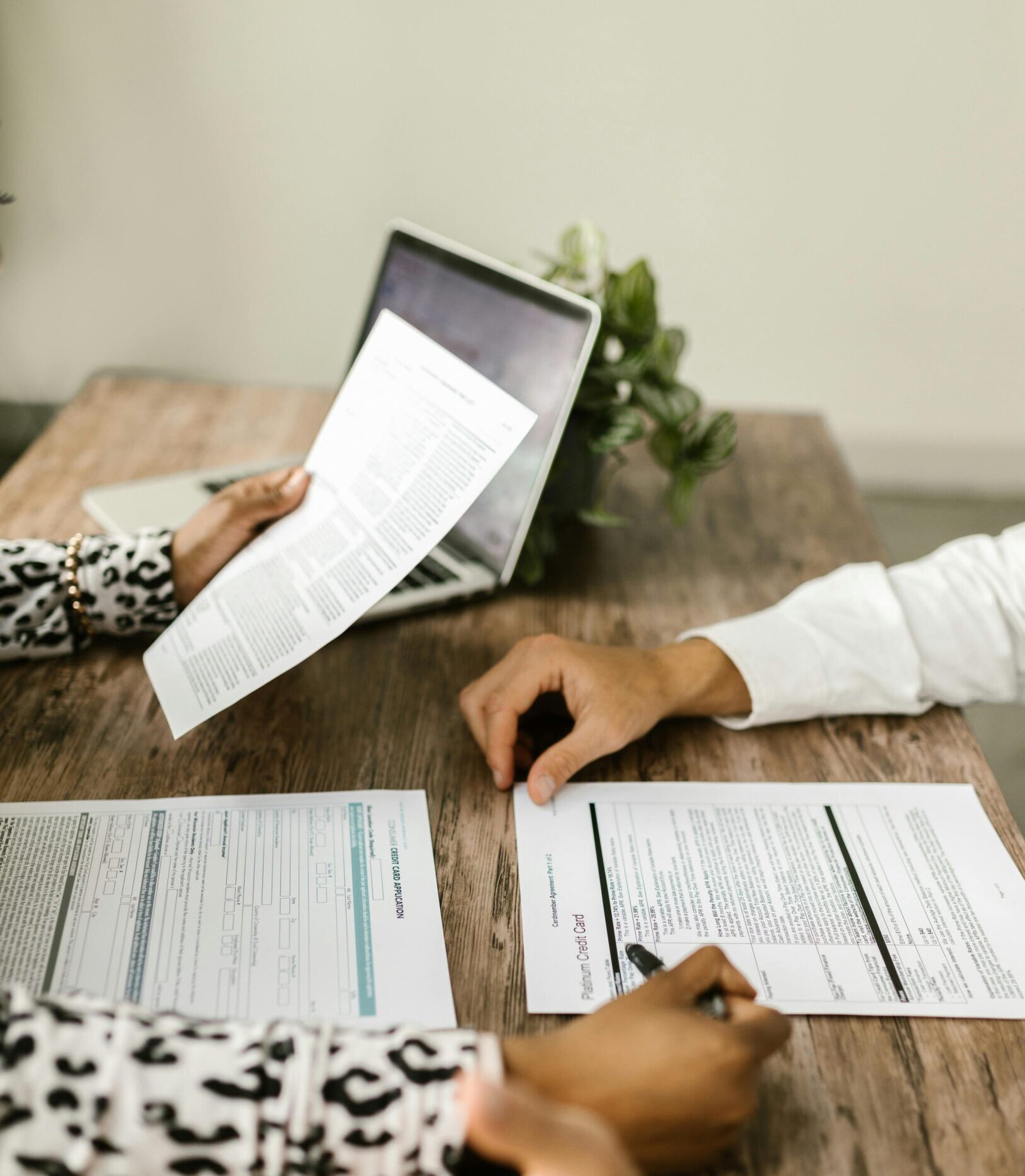 Two people reviewing documents at a wooden table during a business meeting.